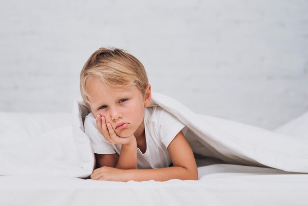 Triste niño quedarse en la cama