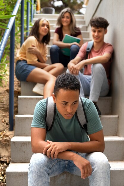 Triste niño sentado en la vista frontal de las escaleras