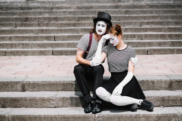 Foto gratuita triste pareja de mimos sentado en la escalera