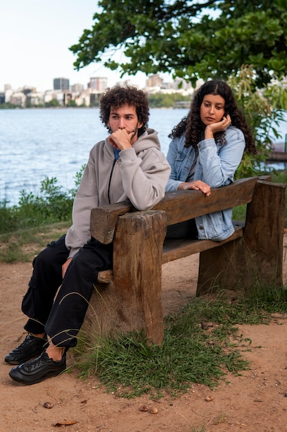 Foto gratuita triste pareja sentada en el banco junto al lago