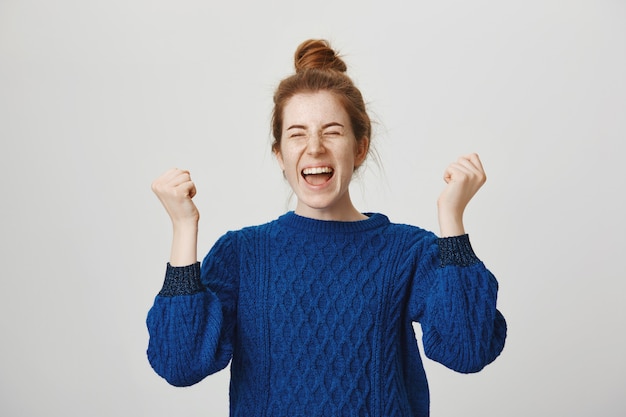 Triunfante linda chica pelirroja celebra el logro, gritando que sí