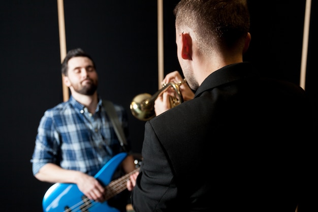 Foto gratuita trompetista y guitarrista en una silla