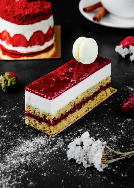 Un trozo cuadrado de tarta de fresa con macarrón blanco en la parte superior.