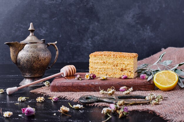 Un trozo de pastel de miel con flores secas y una clásica taza de té en la mesa de mármol.