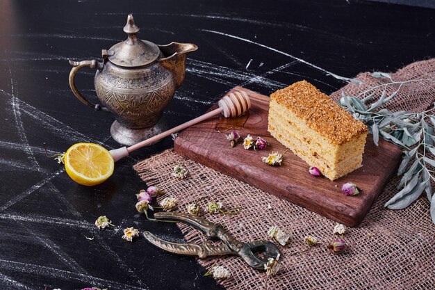 Un trozo de pastel de miel con flores secas sobre una mesa de mármol.