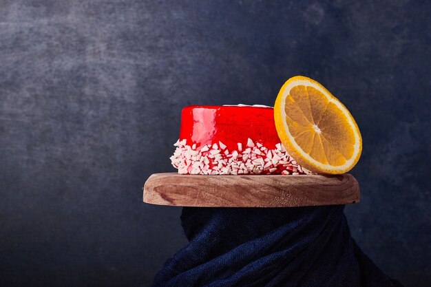 Un trozo de tarta con almíbar rojo y fruta.