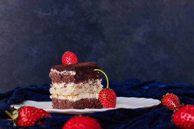 Un trozo de tarta con cacao y fresas.