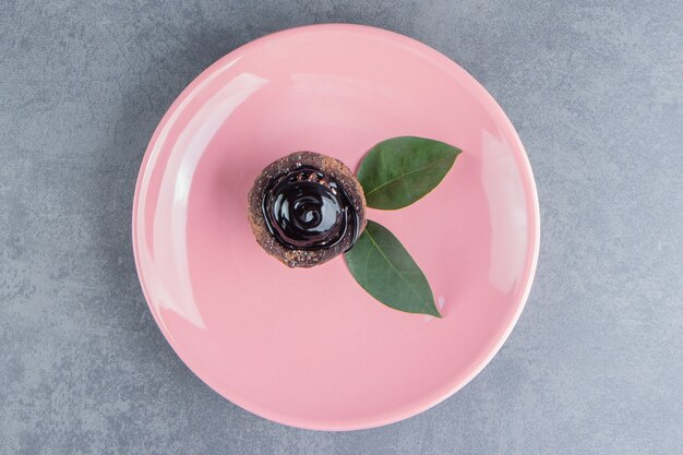 Un trozo de tarta de chocolate con hojas sobre una placa rosa