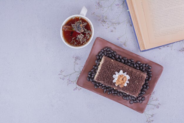 Un trozo de tarta con chocolate picado y una taza de té