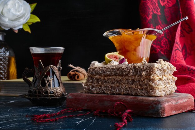 Un trozo de tarta con confitura de cerezas y un vaso de té.