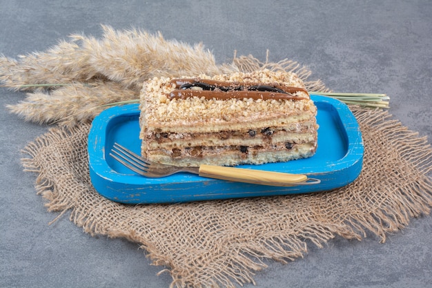 Un trozo de tarta cremosa en placa azul con tenedor.