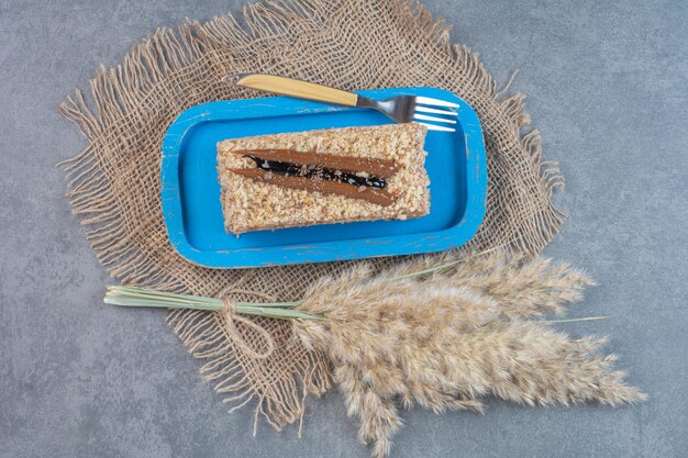 Un trozo de tarta cremosa en placa azul con tenedor