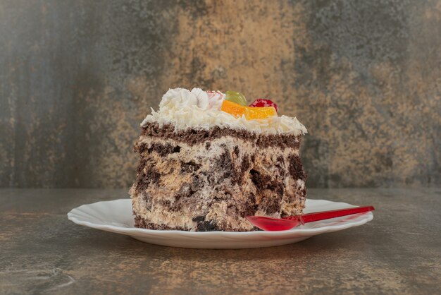 Un trozo de tarta dulce con cuchara roja sobre placa blanca.