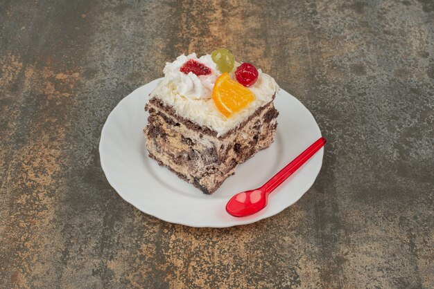 Un trozo de tarta dulce con cuchara roja sobre placa blanca.