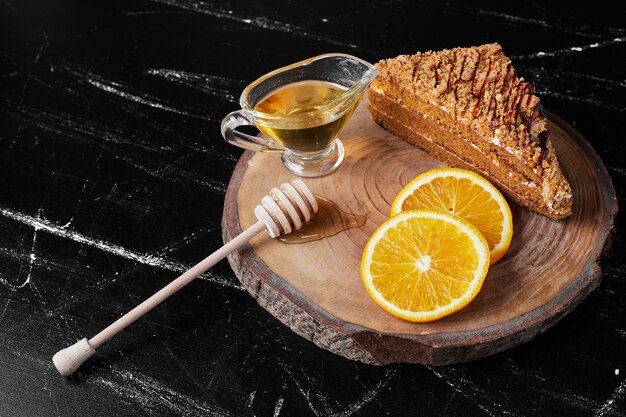 Un trozo de tarta de miel con rodajas de naranja y aceite.