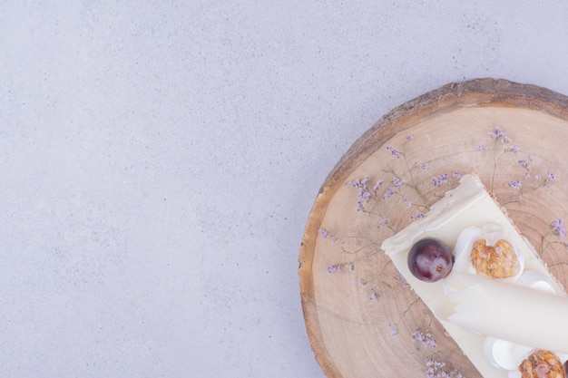 Foto gratuita un trozo de tarta con nueces y uvas sobre tabla de madera.