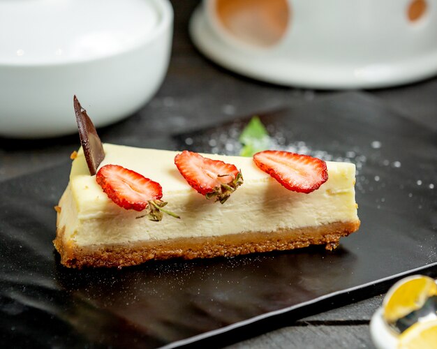 Un trozo de tarta de queso con rodajas de fresa