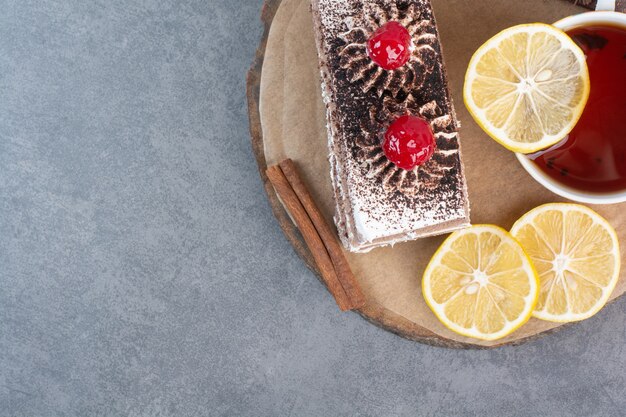 Un trozo de tarta con rodajas de limón y canela sobre tabla de madera.