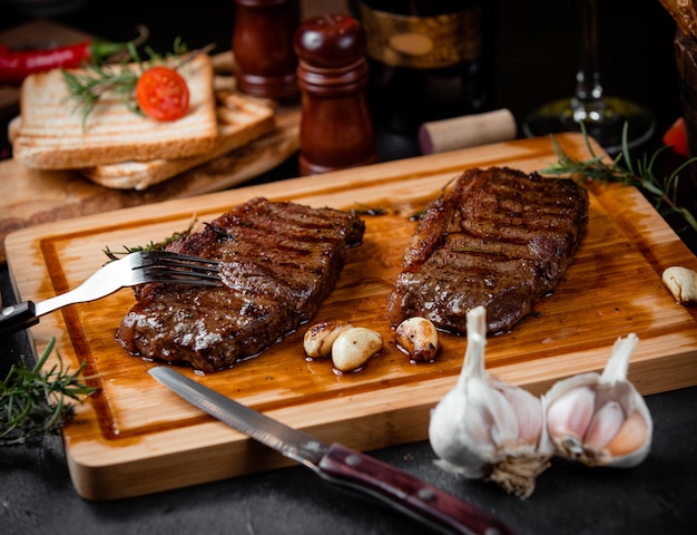 Trozos de carne frita sobre una tabla de madera y ajo