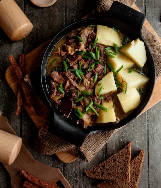 Trozos de carne y papas cocinadas en platos de aluminio.