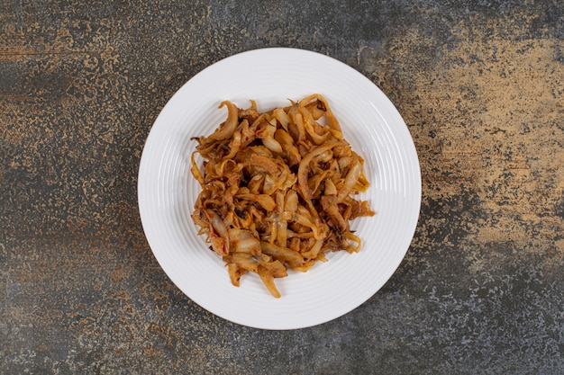 Trozos de cebolla caramelizada en un plato blanco.