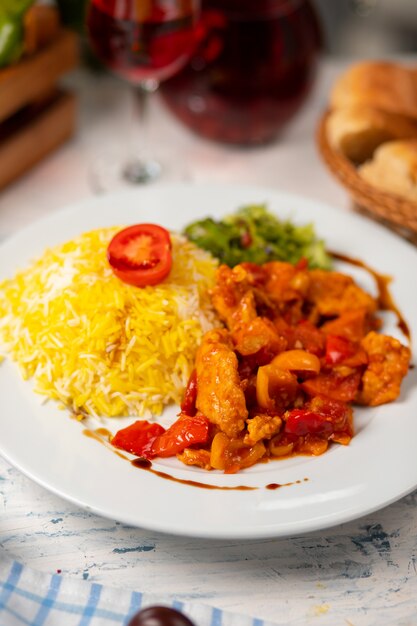 Trozos de pollo y champiñones salteados en salsa de tomate, acompañados de ensalada verde y guarnición de arroz