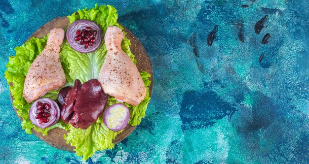 Trozos de pollo crudo con verduras en una placa