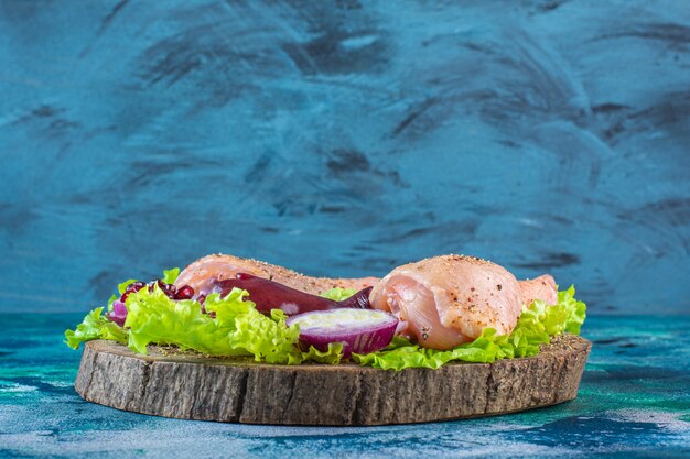 Trozos de pollo crudo con verduras en una placa