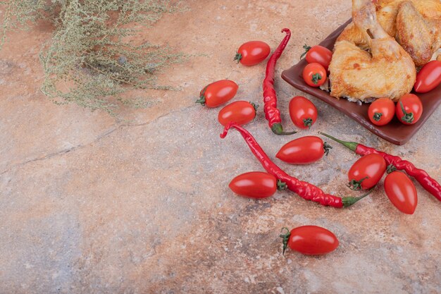 Trozos de pollo frito con pimientos picantes y tomates cherry.