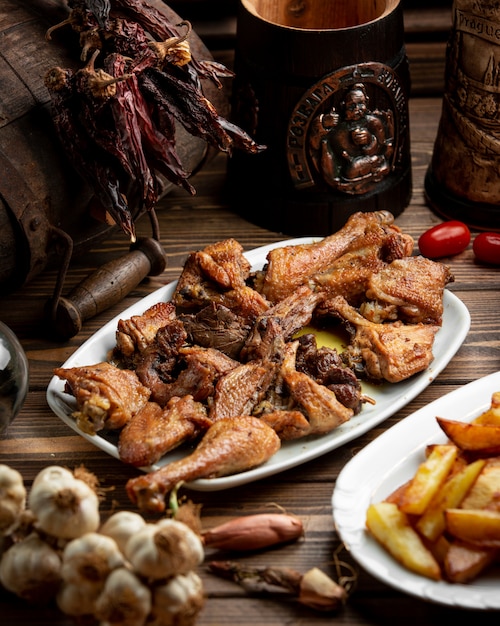 Trozos de pollo a la parrilla y servidor con papas fritas.