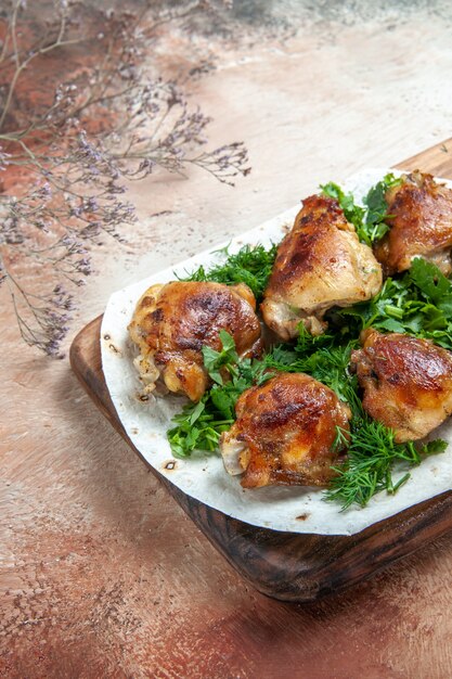 Trozos de pollo de pollo con hierbas en lavash sobre la tabla de cortar de madera