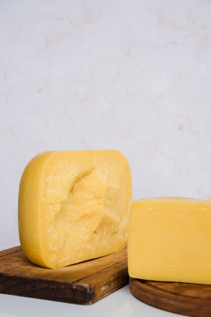 Trozos de queso Gouda en tabla de cortar de madera contra el fondo con textura de mármol