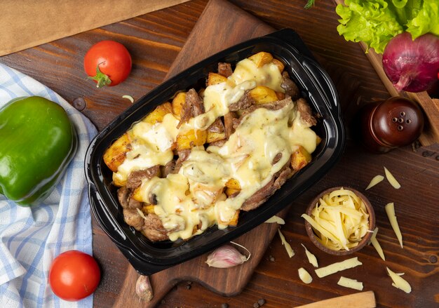 Trozos de ternera asada a la parrilla y rodajas de patata en queso crema fundido