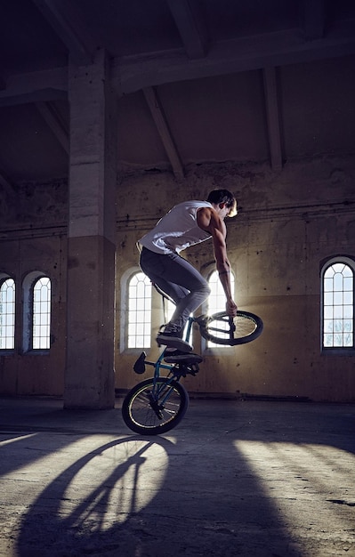 Trucos de BMX y saltos a caballo en un parque interior con luz solar.