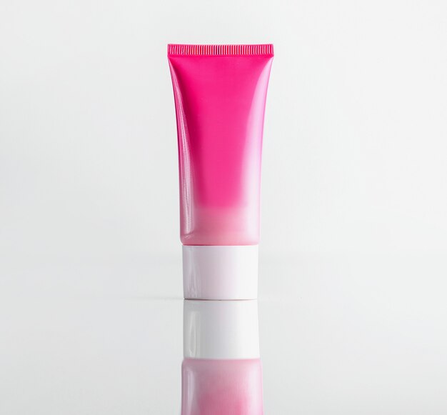 Tubo de vista frontal para tubo de plástico rosa crema con tapa blanca