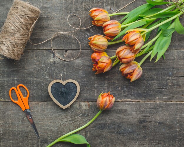 Tulipanes amarillos con hilo rústico en una mesa de madera.