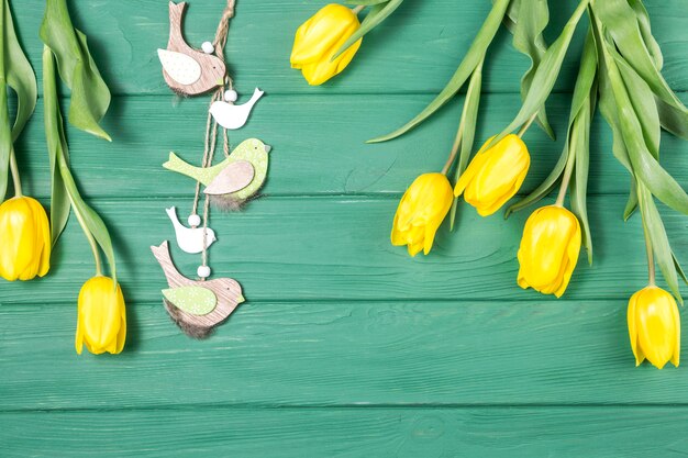 Tulipanes amarillos con pequeños pájaros en mesa