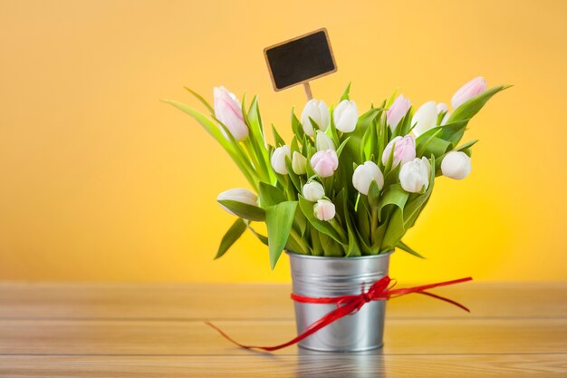 Tulipanes blancos con etiqueta en blanco en maceta
