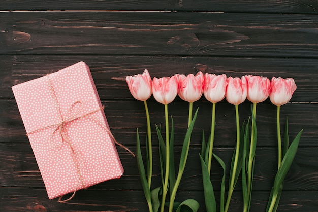 Tulipanes con caja de regalo en mesa de madera.