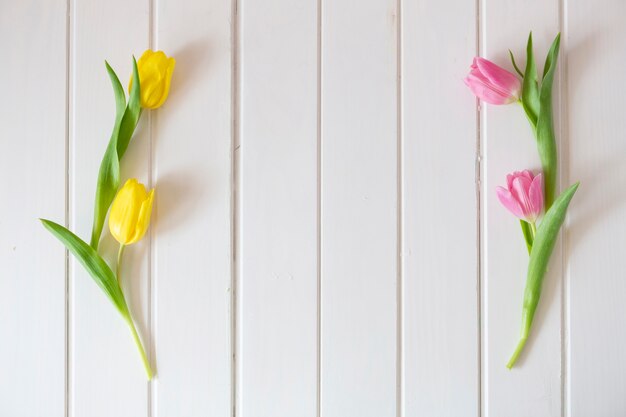 Tulipanes rosa y amarillos sobre superficie de madera