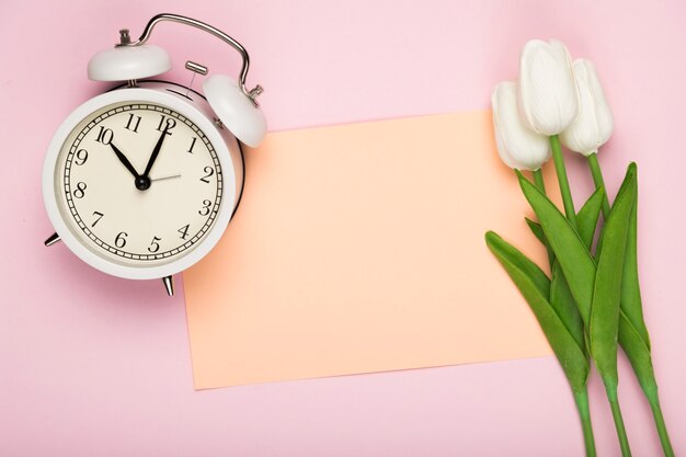 Tulipanes con tarjeta al lado del reloj