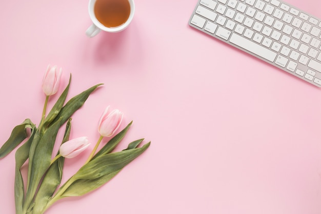 Tulipanes con taza de té y teclado