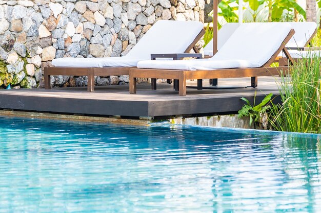 Tumbona vacía alrededor de la piscina al aire libre en el hotel resort para vacaciones de ocio