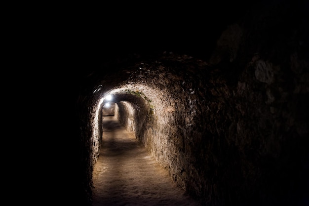 Túnel oscuro y aterrador con algunas luces debajo del castillo.