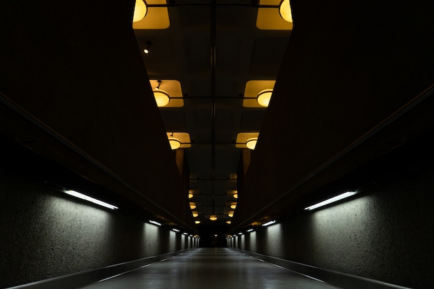 Túnel oscuro con lámparas encendidas en el techo.