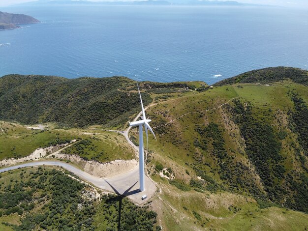Turbina de viento que genera energía en un parque eólico verde con una hermosa vista al mar