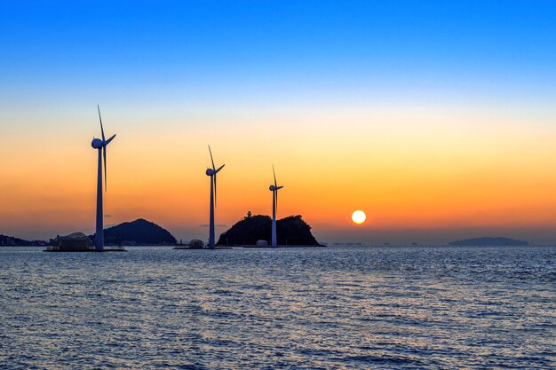 Turbinas de viento que generan electricidad al atardecer en Corea