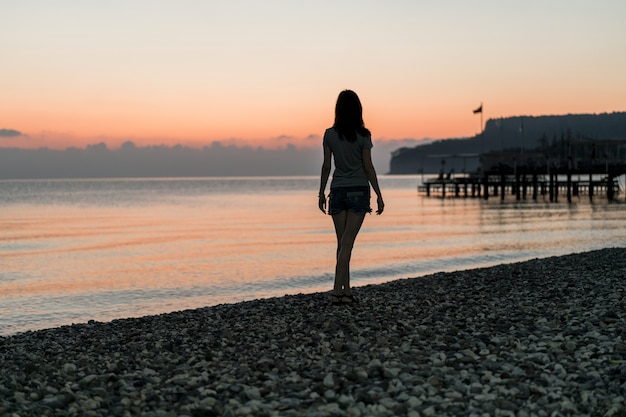 Foto gratuita turista al amanecer caminando por la costa