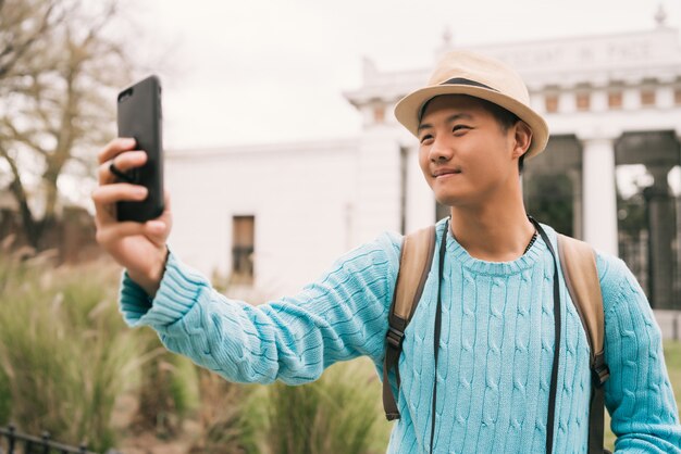 Turista asiático tomando un selfie con teléfono móvil.