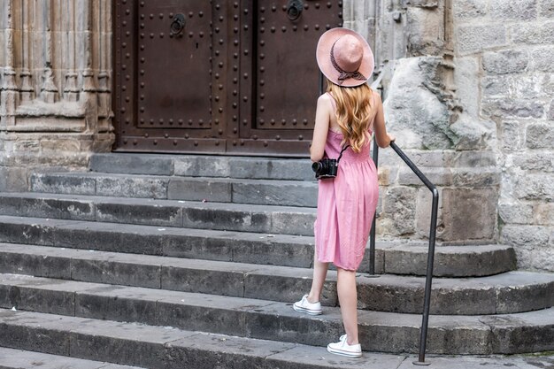 Turista bonita rubia caucásica con un sombrero tomando fotos de la ciudad
